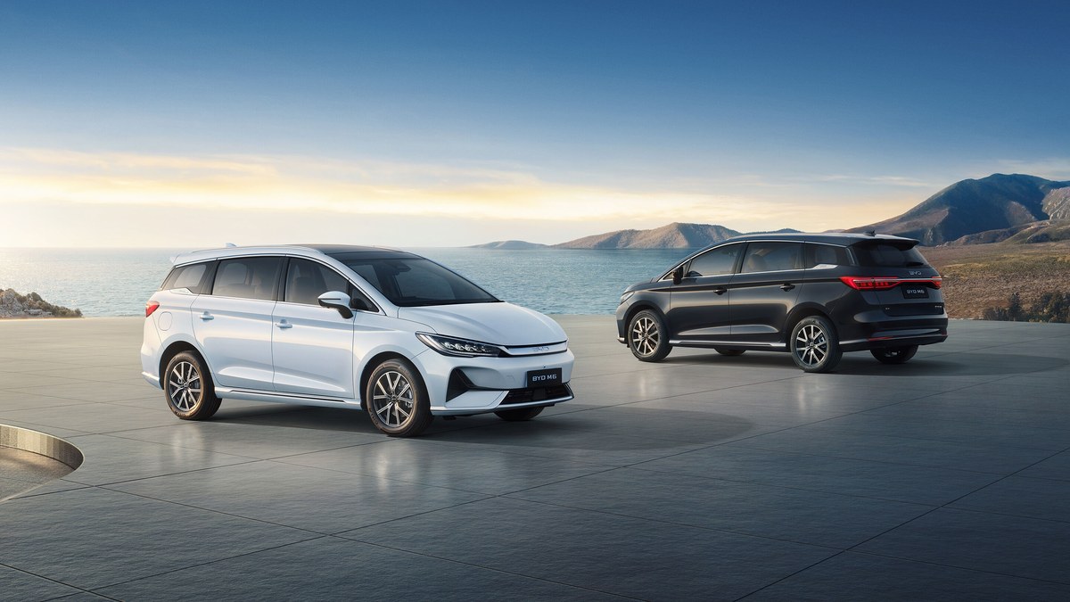 Hai xe BYD M6 màu trắng và đen bên bờ biển, góc nhìn trước và sau